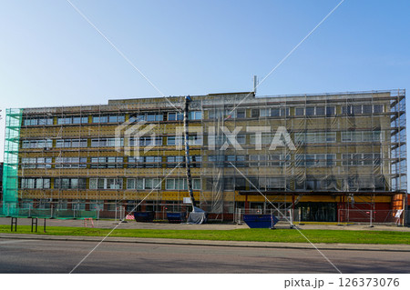 Renovation of office building covered in scaffolding and protective net during reconstruction work 126373076