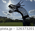 Silhouetted Metal Dragon Sculpture Against Bright Sky 126373201