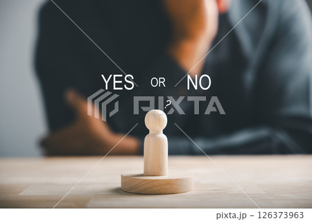 Wooden cube with peg dolls, yes or no choices in business. Man's hand holds two options emphasizing decision-making. Red question mark reinforces the concept. Think With Yes Or No Choice. 126373963