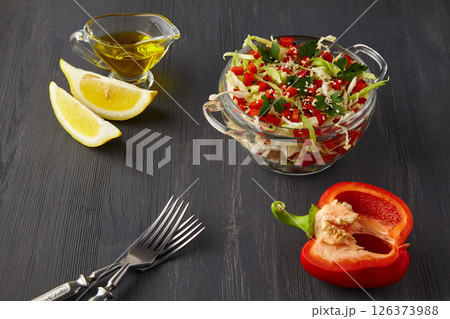 cabbage salad with bell pepper and parsley, sprinkled with sesame seeds, dressed with olive oil and lemon on a black wooden table 126373988