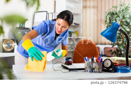 Woman in an overalls cleans table at office 126374796