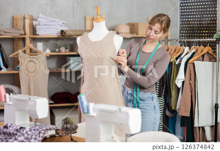 Young female dressmaker working with mannequin in sewing workshop Young female dressmaker working with mannequin in sewing workshop 126374842