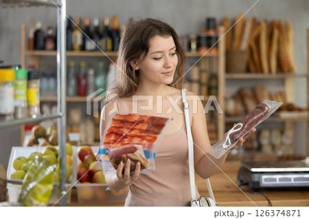 Young girl is choosing dried sausage and meat in grocery store 126374871