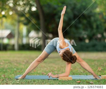 Fitness, sport and healthy lifestyle concept: woman doing yoga pose - vrikshasana pose on mat in park 126374881