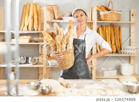 Female baker worker shows many products baguettes Female baker worker shows many products baguettes 126374989