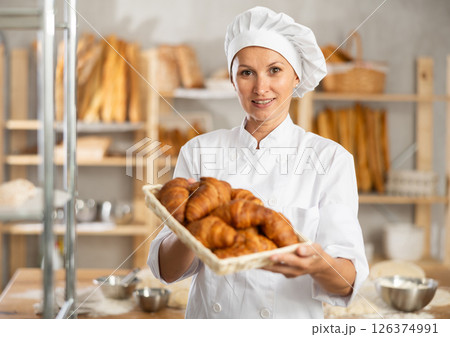 bakery worker shows off a variety of different crescent-shaped buns. 126374991