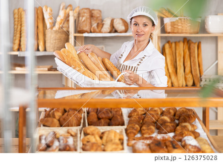 Female baker worker sells baguette, shows many products 126375028