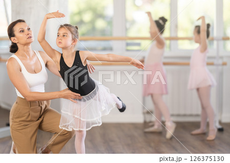 In studio, mentor corrects girls arm and leg, teaches correct dynamics and execution of movements 126375130