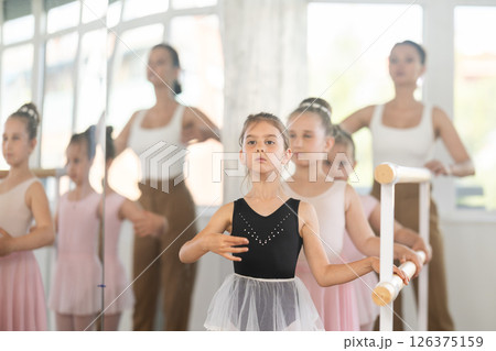 Girls in ballet class perform third position with correction of female mentor 126375159