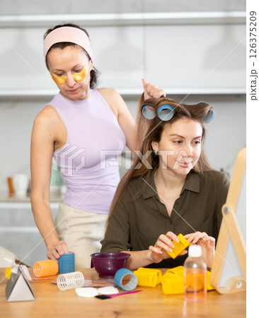 Adult woman curls hair of young woman 126375209