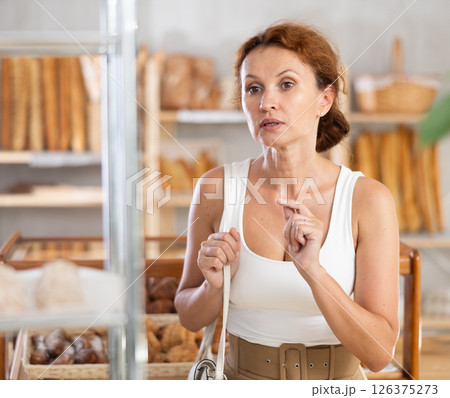 Female customer choosing bread and other delicious pastries in bakery 126375273