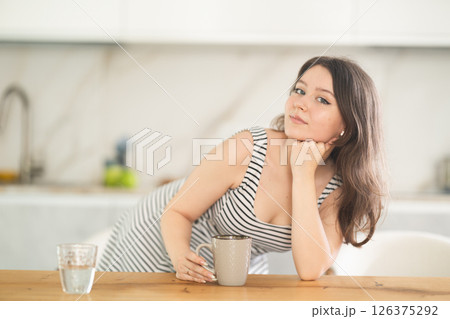 Young woman with cup leaning on table 126375292