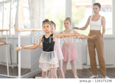 Girls in ballet class perform second position with correction of female mentor Girls in ballet class perform second position with correction of female mentor 126375296