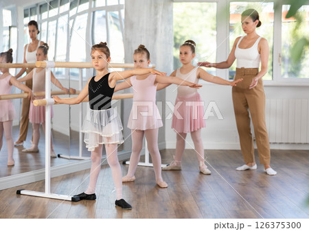 Little girls at the barre learning to get into second position of ballet choreography Little girls at the barre learning to get into second position of ballet choreography 126375300