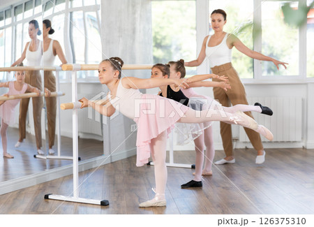 Little girls ballet lovers learn to perform arabesque pose in choreography studio Little girls ballet lovers learn to perform arabesque pose in choreography studio 126375310