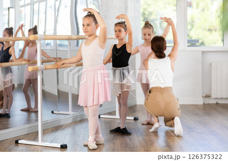 Woman teacher corrects group of girls in third position Woman teacher corrects group of girls in third position 126375322