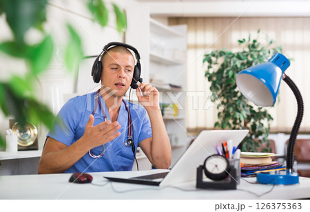 Doctor in headphones consults patient using laptop and the Internet. Virtual visit to hospital concept Doctor in headphones consults patient using laptop and the Internet. Virtual visit to hospital concept 126375363