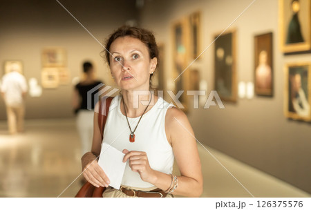 Closeup on attentive woman visiting museum and looking at exhibition of paintings Closeup on attentive woman visiting museum and looking at exhibition of paintings 126375576