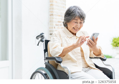 スマートフォンを操作する車椅子のシニア女性 126375858
