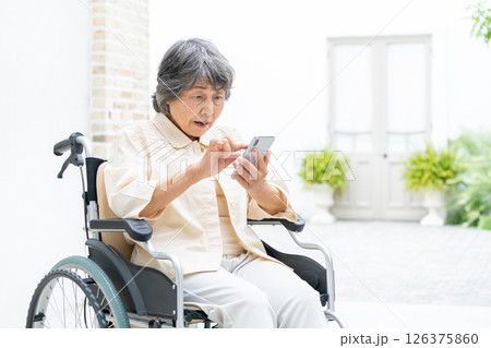 スマートフォンを操作する車椅子のシニア女性 126375860