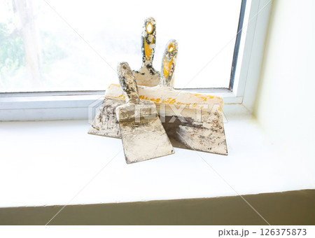 Construction spatulas lie on the windowsill after work 126375873