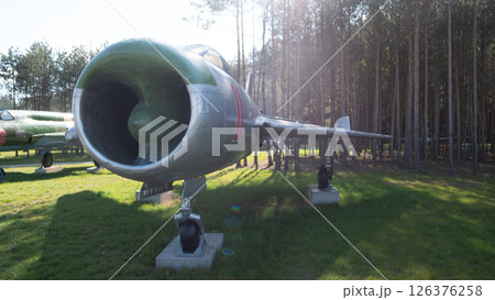 A vintage Soviet aircraft stands prominently in a museum nestled among tall trees, representing a significant piece of military and aviation heritage from the USSR. 126376258