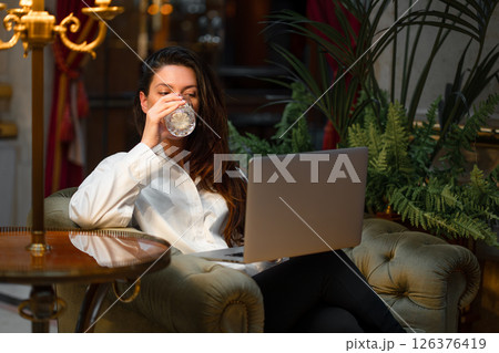 Businesswoman with laptop drinking alcohol sitting 126376419