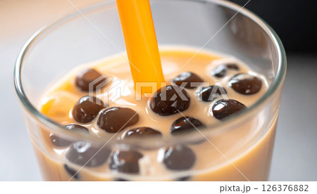 A close-up of bubble tea with an orange straw and tapioca pearls. A close-up of bubble tea with an orange straw and tapioca pearls. 126376882