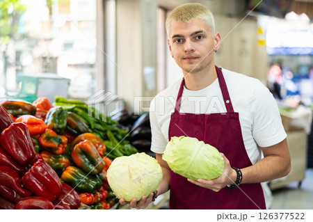 Grocery store employee places ripe cabbage on a display case at supermarket Grocery store employee places ripe cabbage on a display case at supermarket 126377522