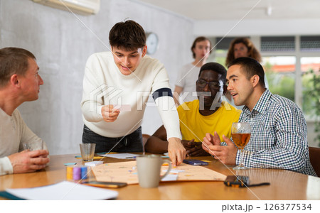 Cheerful guy playing board game with male friends 126377534