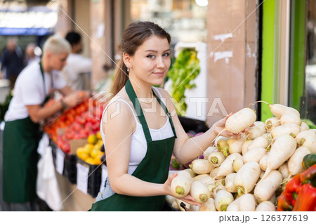 Female seller offering daikon Female seller offering daikon 126377619