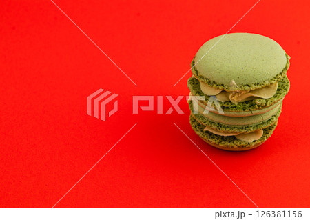 Delightful green macarons stacked on vibrant red backdrop 126381156