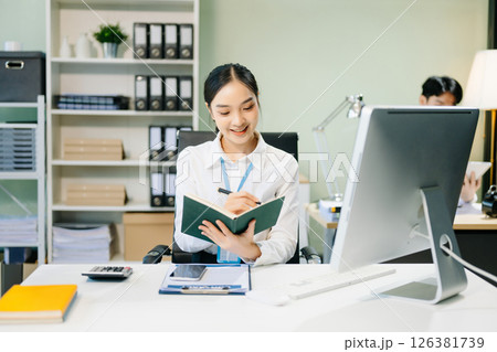 Asian female office worker business suits smiling at camera with working notepad, tablet and laptop documents 126381739