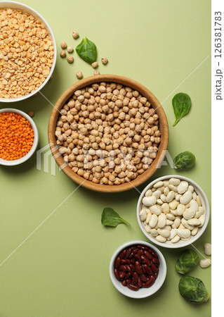 Beans in bowls on green background, top view 126381783