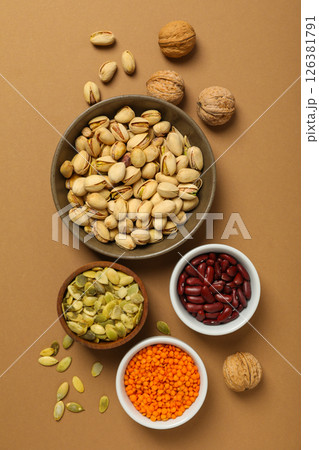 Beans, nuts and seeds in bowls on beige background, top view 126381791