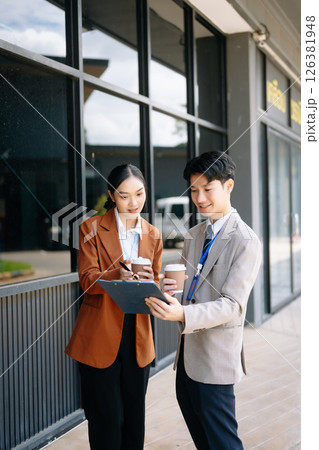 Businessman and woman going in city center in smart casual business style, talking, working together, stylish freelance people, holding coffee Businessman and woman going in city center in smart casual business style, talking, working together, stylish freelance people, holding coffee 126381948