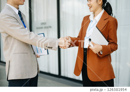 Business people shaking hands during a meeting. Two happy young businessmen and businesswoman Business people shaking hands during a meeting. Two happy young businessmen and businesswoman 126381954
