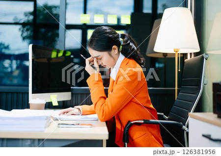 Asian woman feeling migraine head strain.Overworked businesswoman financier while working 126381956