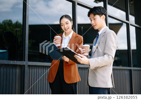 Businessman and woman going in city center in smart casual business style, talking, working together, stylish freelance people, holding coffee 126382055