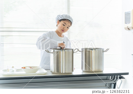 白衣を着て大鍋の料理を配膳する給食当番の女の子 白衣を着て大鍋の料理を配膳する給食当番の女の子 126382231