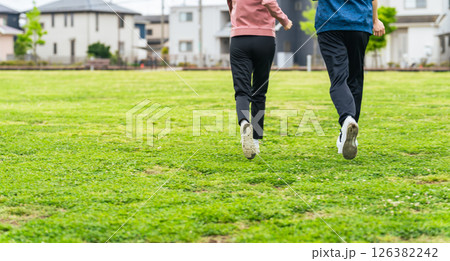 芝生の公園を走るカップルの後ろ姿 芝生の公園を走るカップルの後ろ姿 126382242