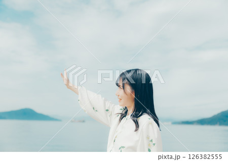 静かな海辺に佇む白い服の女性 126382555