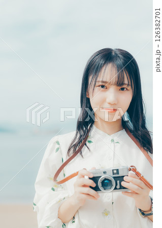 砂浜でフィルムカメラを構える少女 126382701