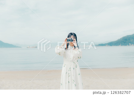 砂浜でフィルムカメラを構える少女 砂浜でフィルムカメラを構える少女 126382707