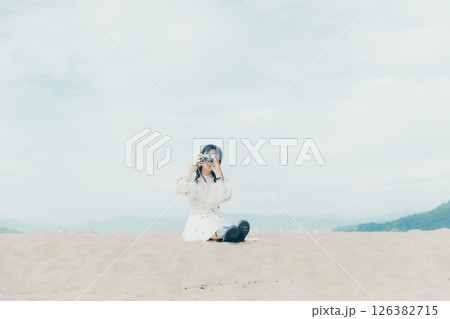 砂浜でフィルムカメラを構える少女 砂浜でフィルムカメラを構える少女 126382715
