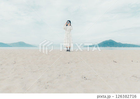 砂浜でフィルムカメラを構える少女 126382716