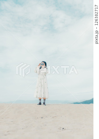 砂浜でフィルムカメラを構える少女 砂浜でフィルムカメラを構える少女 126382717
