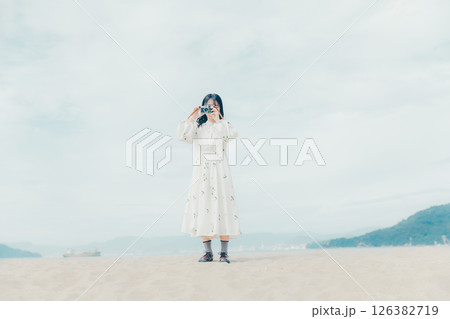 砂浜でフィルムカメラを構える少女 砂浜でフィルムカメラを構える少女 126382719