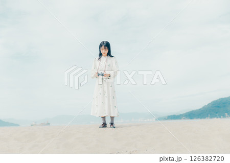 砂浜でフィルムカメラを構える少女 砂浜でフィルムカメラを構える少女 126382720