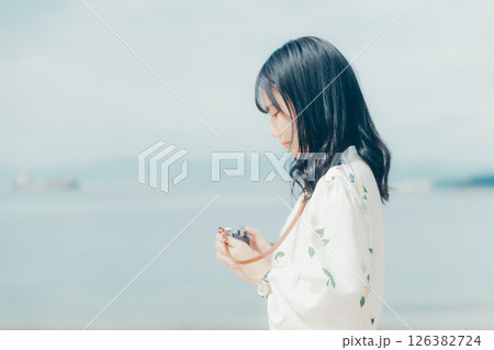 砂浜でフィルムカメラを構える少女 砂浜でフィルムカメラを構える少女 126382724